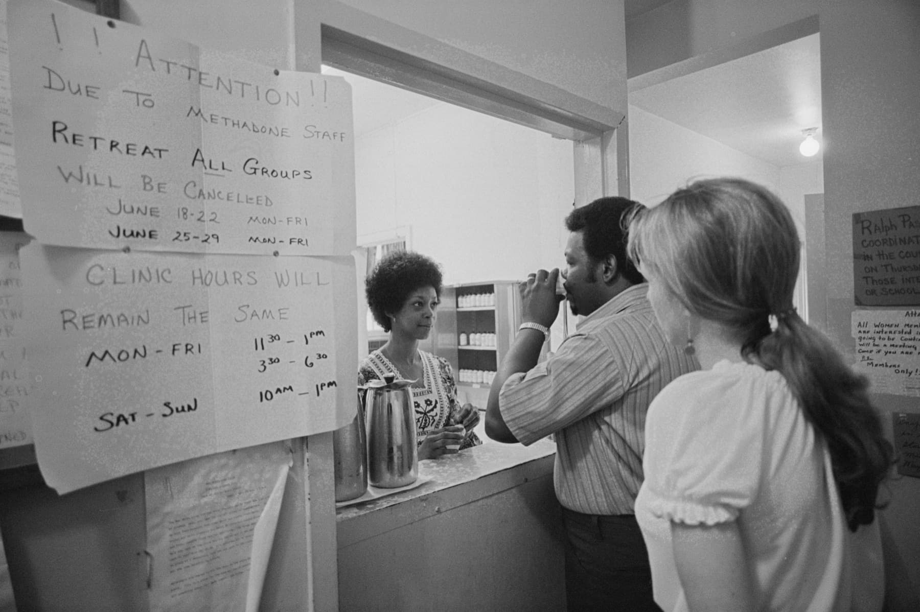 A man drinks his methadone dose at a clinic dispensing window in 1973, with a nurse behind the counter